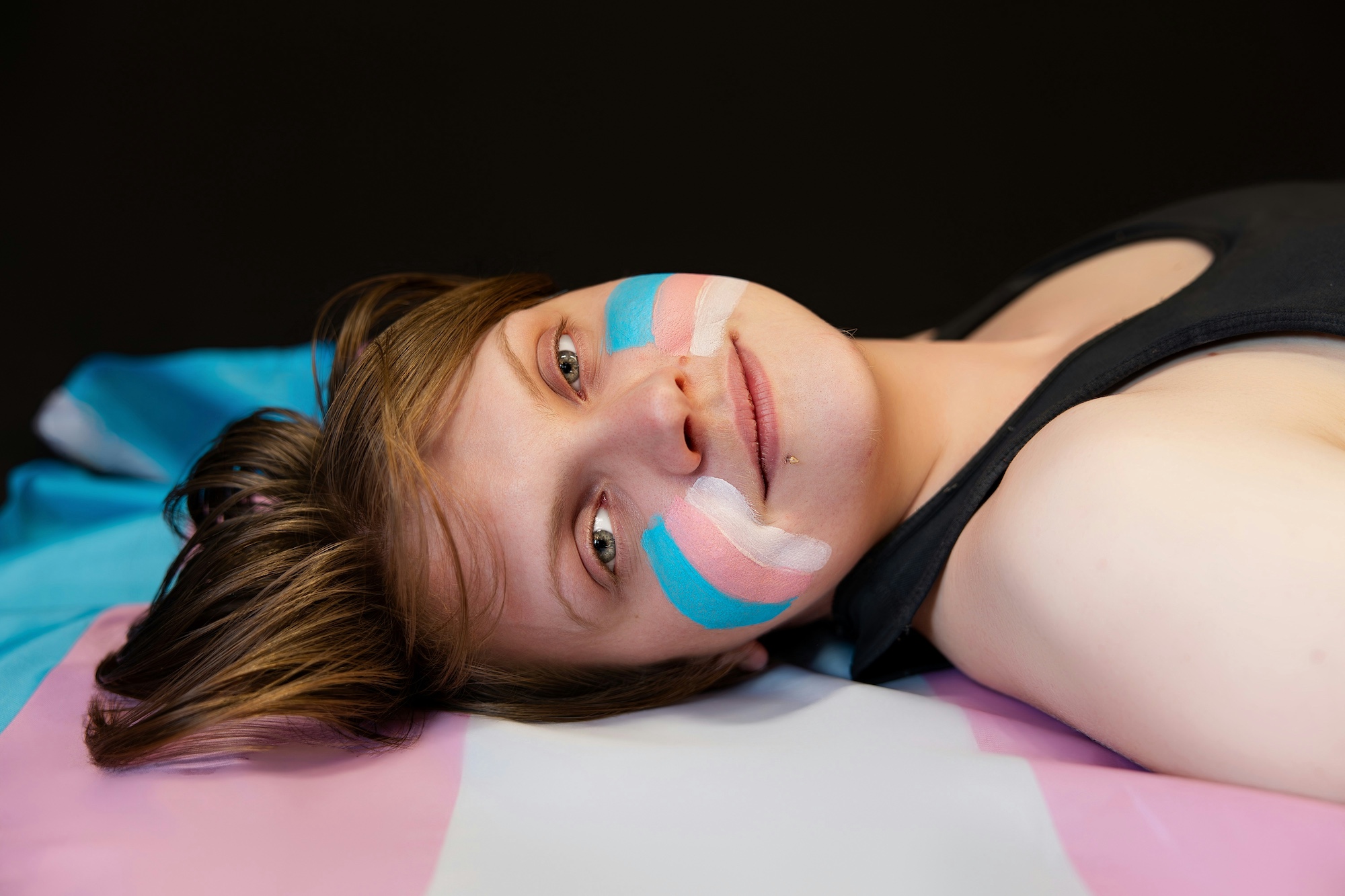 person lying on a transgender flag